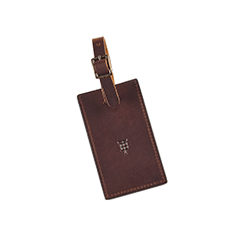 Brown leather luggage tag with a buckle strap and embossed design in the center.