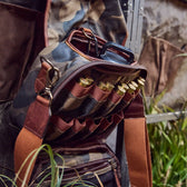 Open Tom Beckbes Classic Camo Blind Bag with double-shell pockets, revealing shotgun shells on grass and a dangling strap.