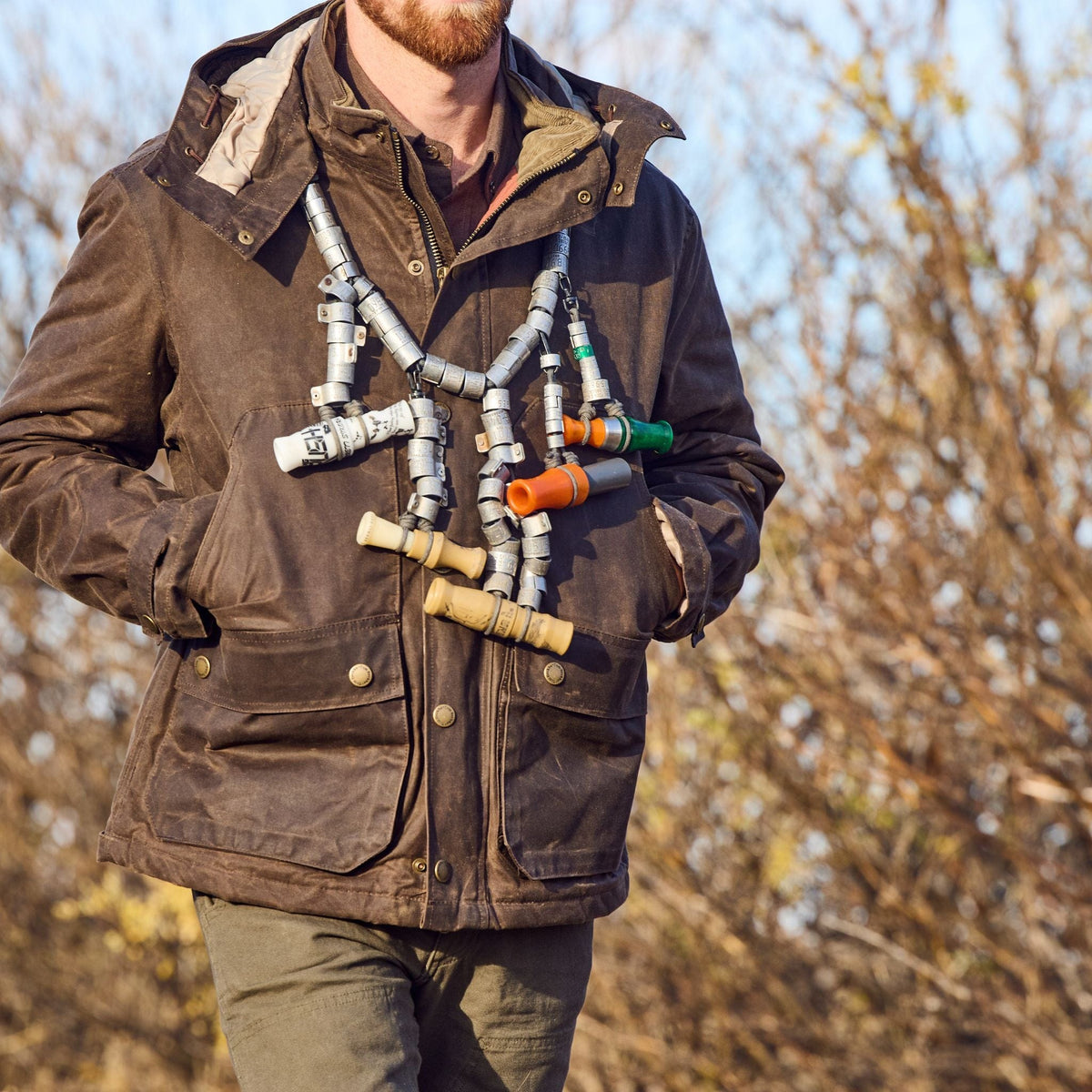 A person in a Tom Beckbe Fowler Jacket with metal fittings stands outdoors, trees in the background.