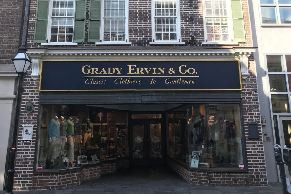 Storefront of Grady Ervin & Co. with a sign reading Classic Clothiers To Gentlemen and various clothing displays inside.