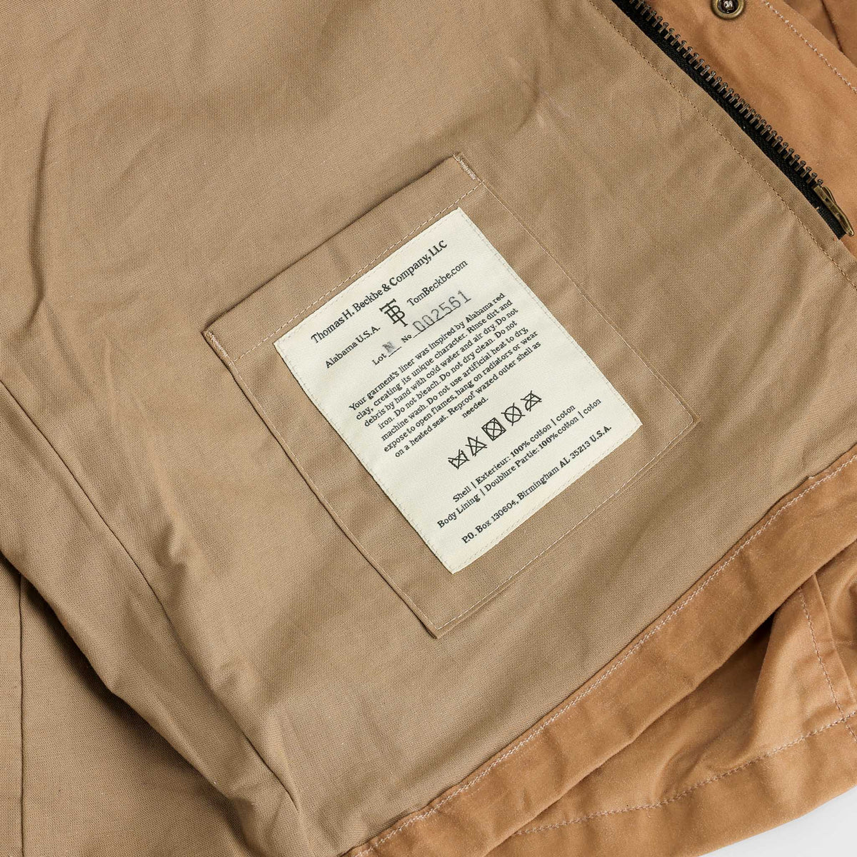 Close-up of the Tom Beckbe Kinsman Vest in tan with a white sewn-in label displaying care and product details.