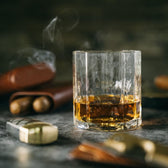 A Terrane No. 12 Glass by Tom Beckbe holds whiskey with cigars in the background.
