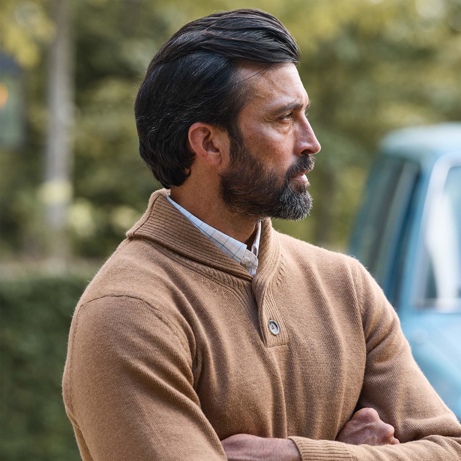 Man in Tom Beckbe's Henry Shawl Sweater in Royal Alpaca stands outdoors, arms crossed, looking to the side.