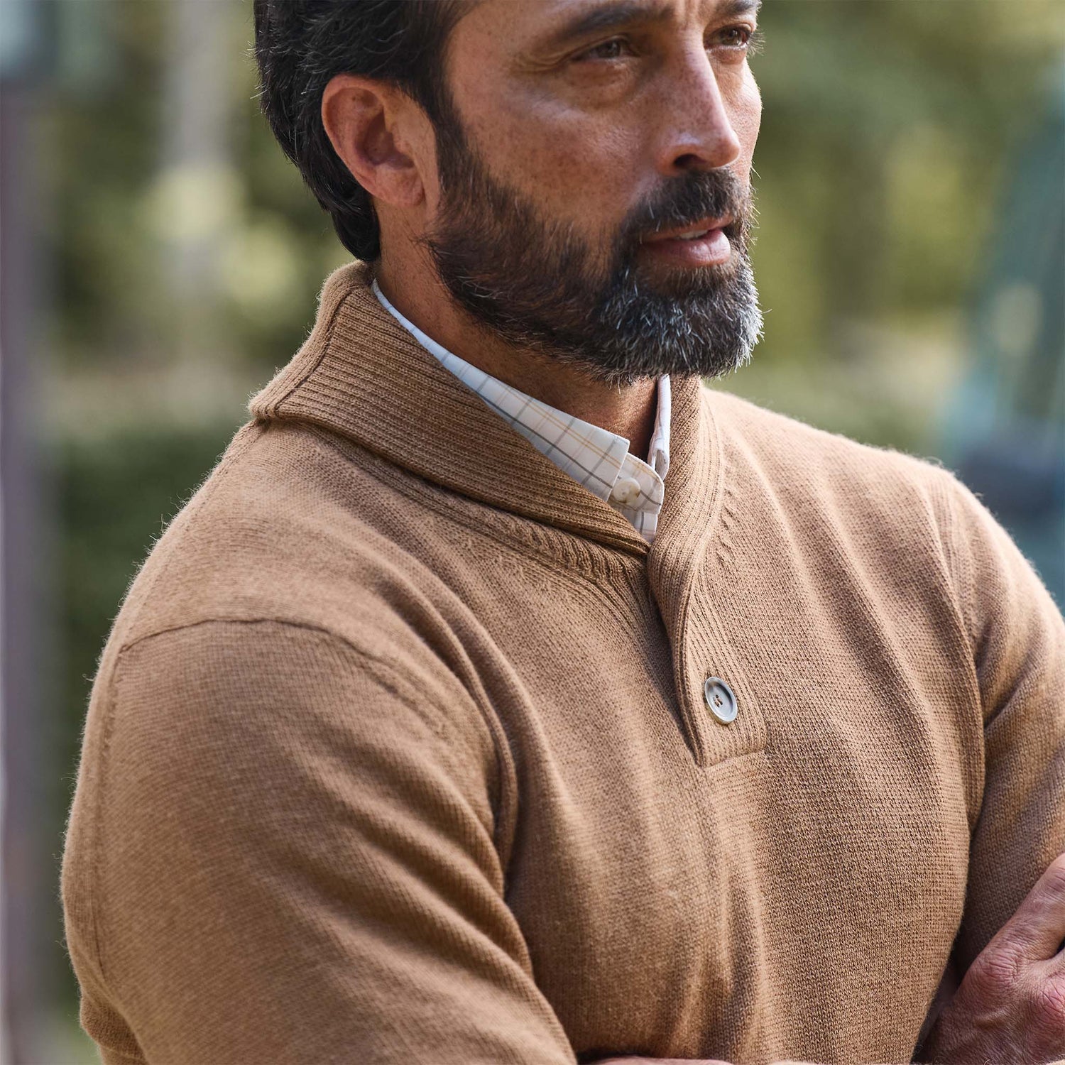 Man with a beard in Tom Beckbe's Henry Shawl Sweater in Royal Alpaca, standing outdoors with arms crossed.