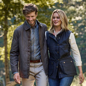 A man and woman enjoy a sunny walk wearing Tom Beckbes Braddock Quilted Jackets, looking content and relaxed.