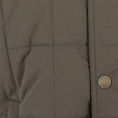 Close-up of the Tom Beckbe Burgess Quilted Vest in khaki, with visible stitching and a branded round metallic button.