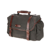 The Canvas Field Bag by Tom Beckbe features rugged green waxed canvas, brown leather straps, brass buckles, and side pockets.
