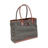 The Tom Beckbe Canvas Tote is durable, featuring green canvas, brown leather handles, a front pocket, and a reinforced bottom.