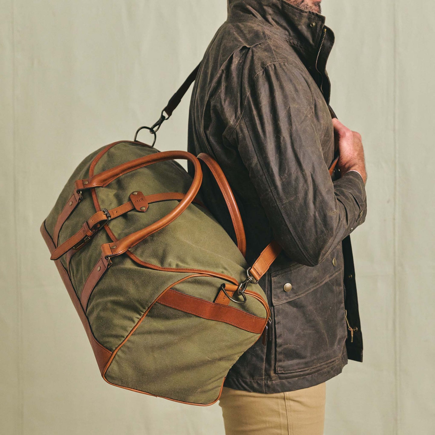 A person carries the Tom Beckbe Canvas Weekender Duffel Bag over their shoulder.