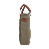 Side view of the Tom Beckbe Canvas Whiskey Tote in olive green with brown leather handles and accent patch.