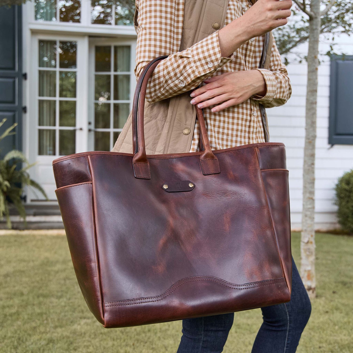 A woman holding the Tom Beckbe Covington Leather Carryall Bag with a waterproof interior.