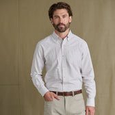 Man in Tom Beckbe Culver Oxford Shirt and light khaki pants stands against a plain brown background.