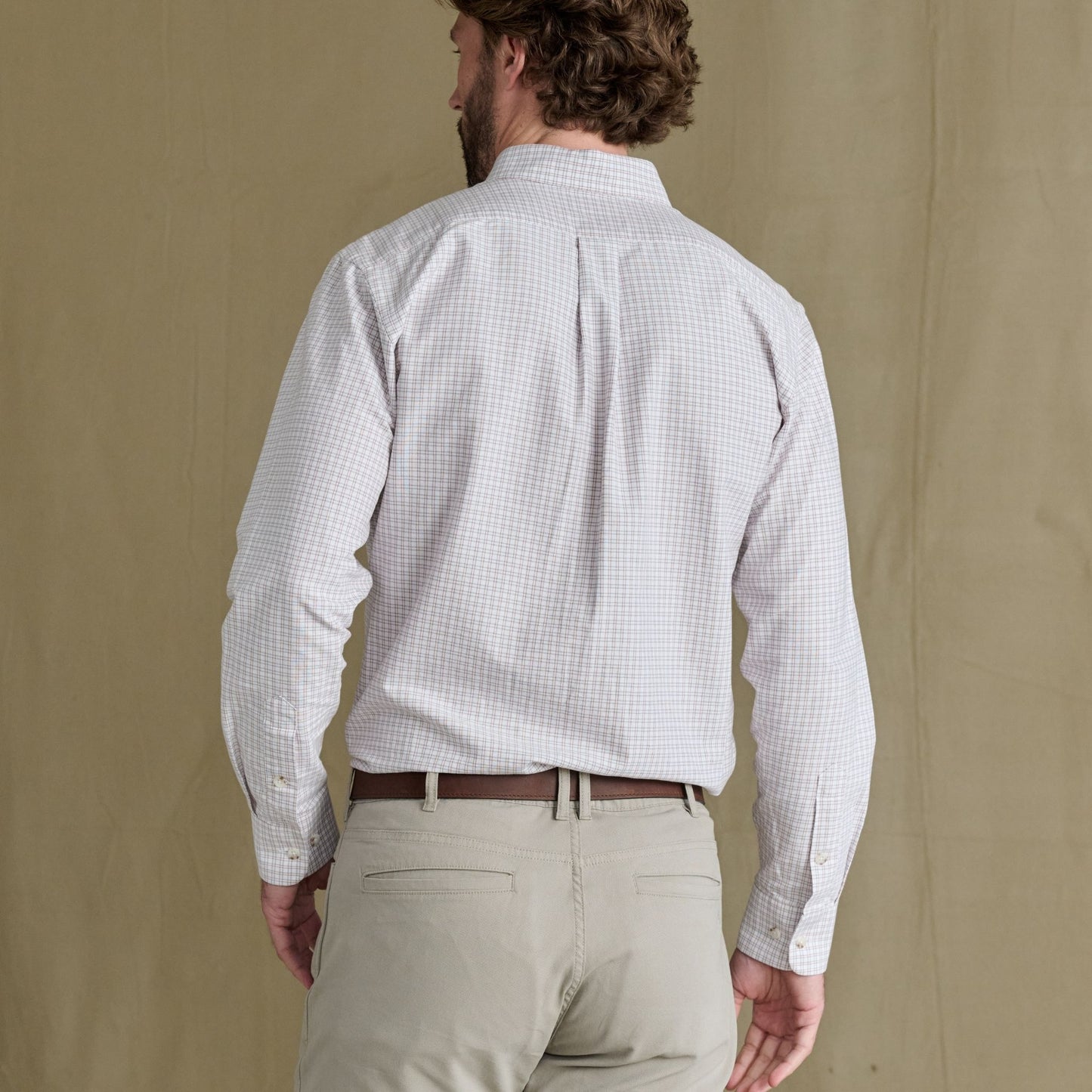 Man in a Tom Beckbe Culver Oxford Shirt and beige pants stands with his back to the camera.