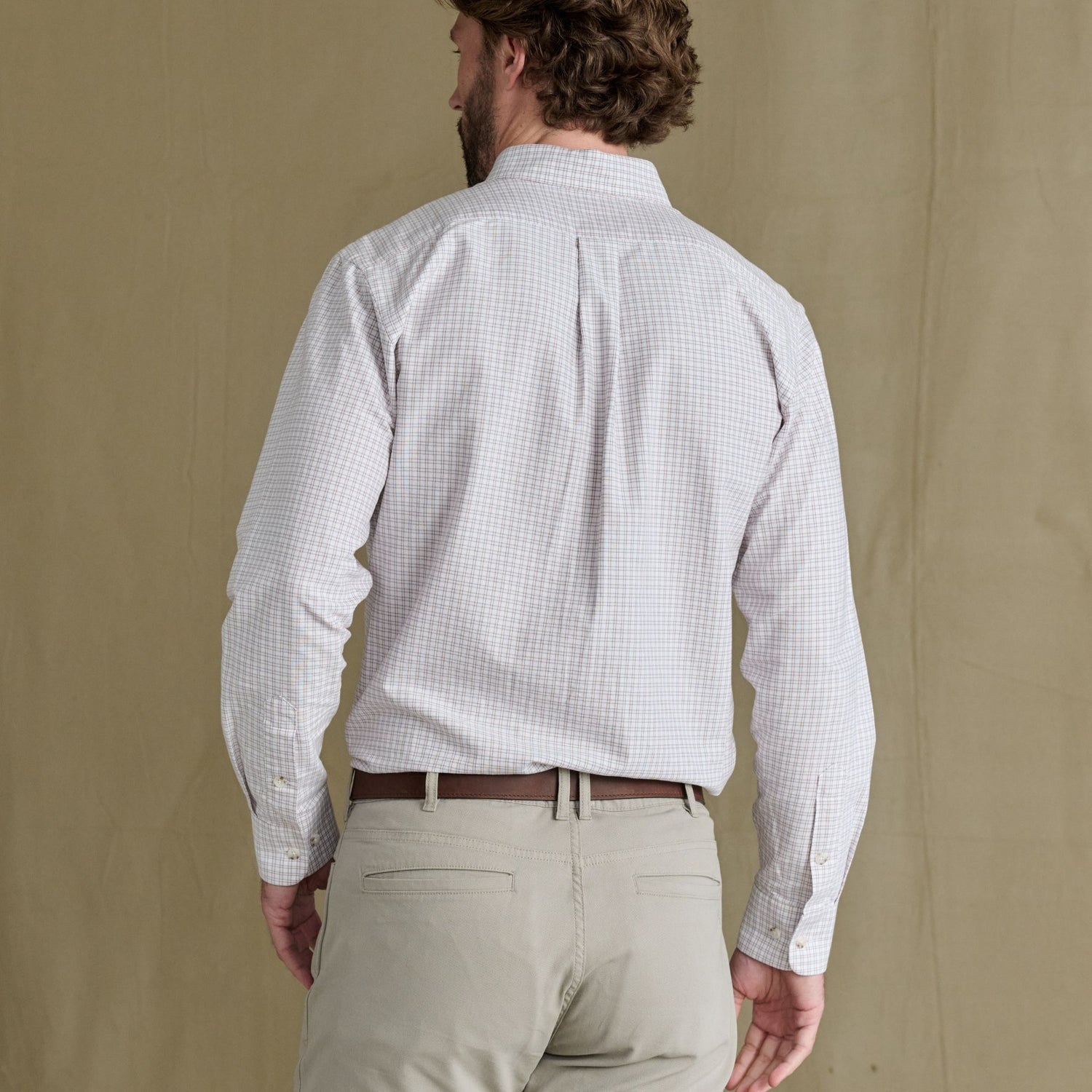 Man in a Tom Beckbe Culver Oxford Shirt and beige pants stands with his back to the camera.
