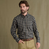Man in a Tom Beckbe Dixon Brushed Cotton Twill Shirt and khakis stands before a khaki backdrop, hand in pocket.