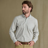 Bearded man in Tom Beckbe Ensley Pinpoint Oxford Shirt and khaki pants stands before a plain beige background.