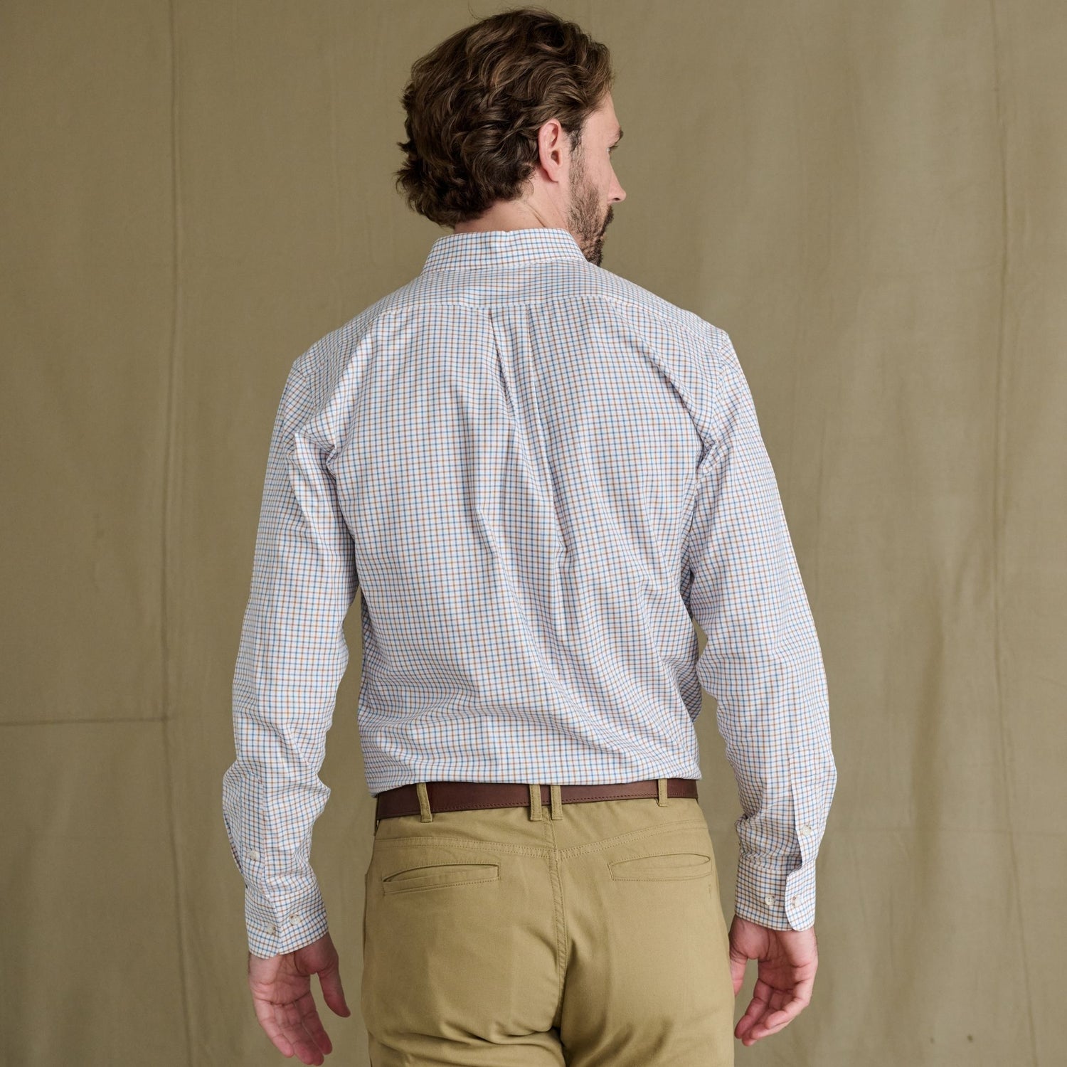 Man with short hair wears Tom Beckbe Ensley Pinpoint Oxford Shirt and khaki pants, facing away against plain background.