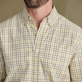 Man wears Tom Beckbe Ensley Pinpoint Oxford, plaid with red, yellow, blue lines; shown neck to chest.