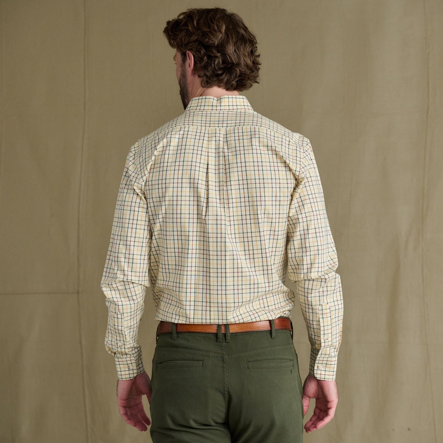 Man seen from behind in a Tom Beckbe Ensley Pinpoint Oxford Shirt, green pants, and a brown belt.