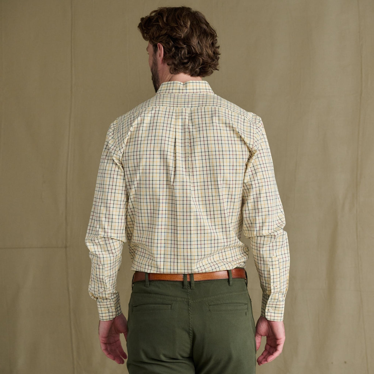 Man seen from behind in a Tom Beckbe Ensley Pinpoint Oxford Shirt, green pants, and a brown belt.