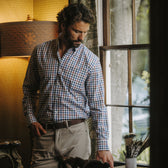 Man in Tom Beckbe Ensley Pinpoint Oxford Shirt and khakis stands by a window in a room with vintage decor.