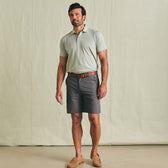 Man wearing a light gray Tom Beckbe Hutton Performance Polo, brown belt, dark gray shorts, and brown loafers.