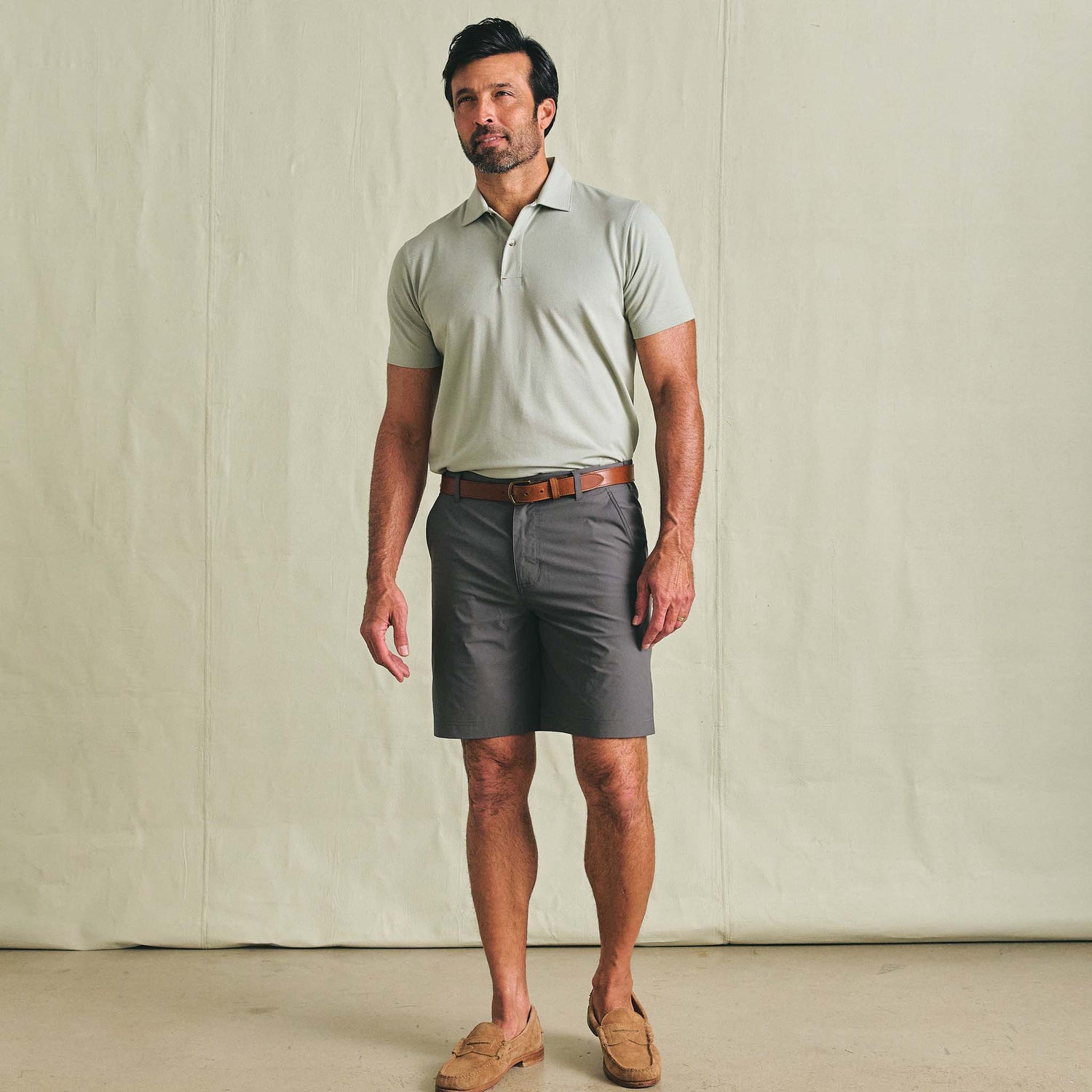 Man wearing a light gray Tom Beckbe Hutton Performance Polo, brown belt, dark gray shorts, and brown loafers.
