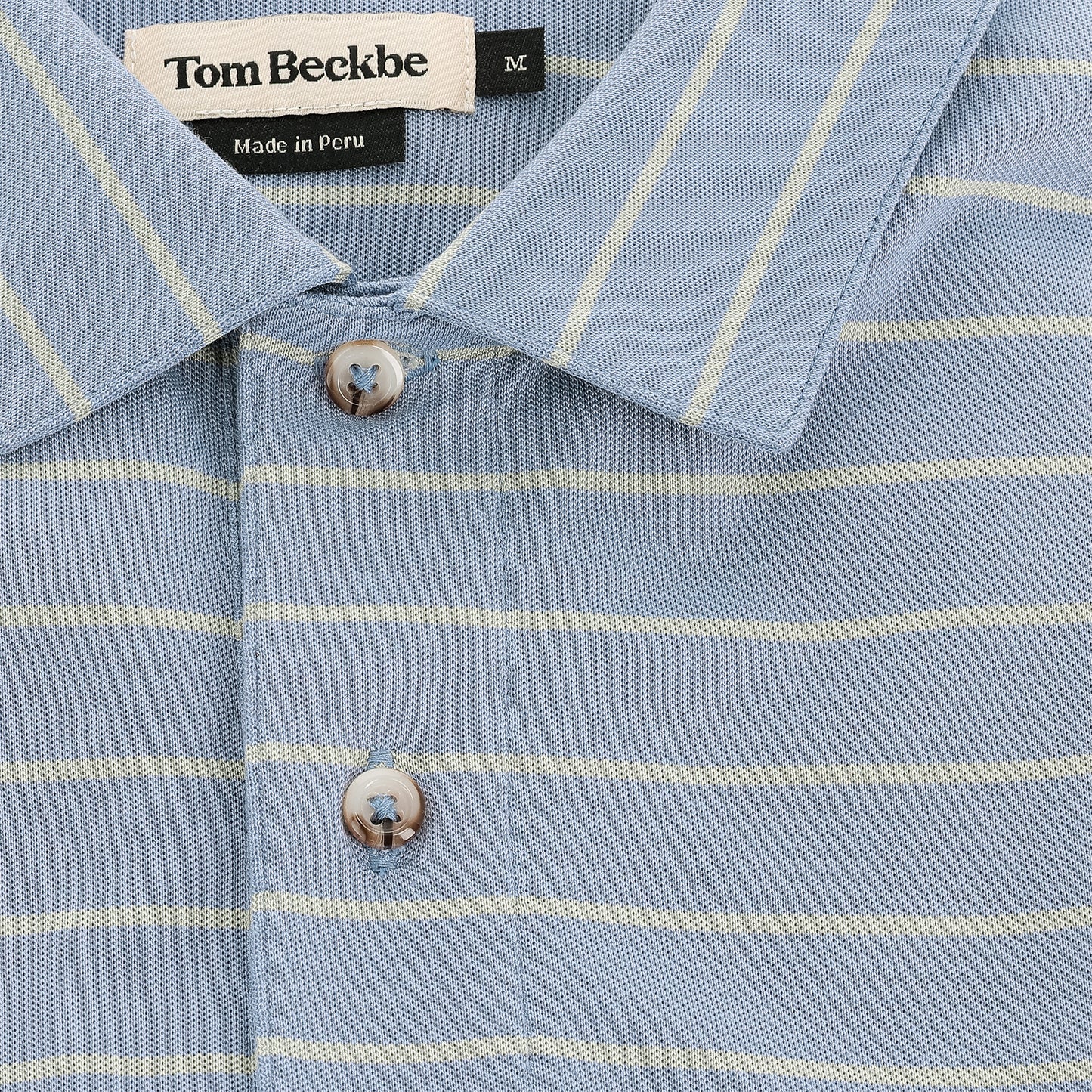 Close-up of Tom Beckbe's Hutton Performance Polo for men in blue with yellow stripes and button placket.