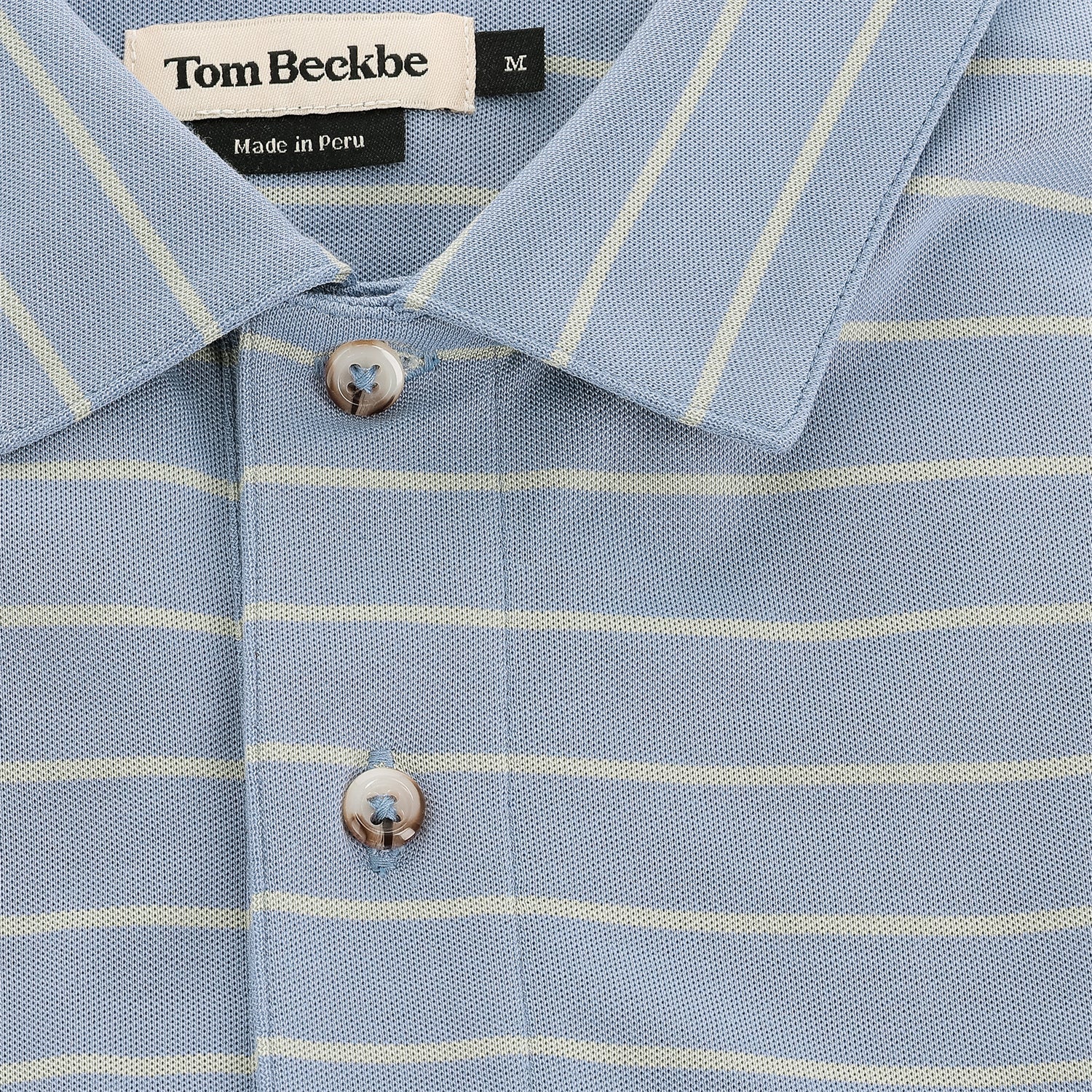 Close-up of Tom Beckbe's Hutton Performance Polo for men in blue with yellow stripes and button placket.