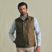 A man wears the Tom Beckbe Kinsman Vest over a light blue shirt, standing against a plain beige background.