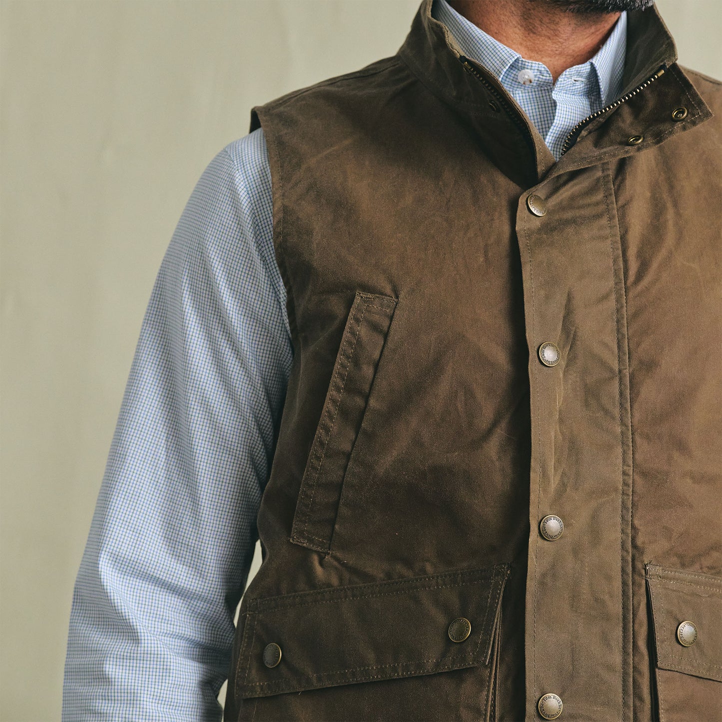 A person wears the Tom Beckbe Kinsman Vest over a light blue patterned dress shirt against a plain background.