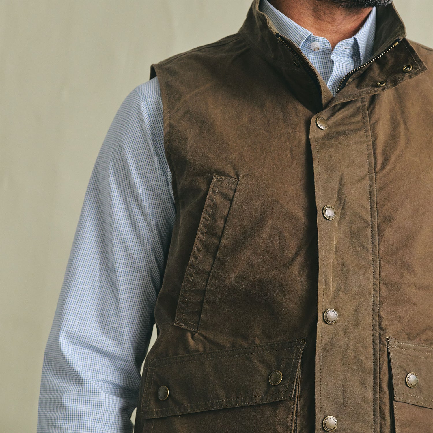 A person wears the Tom Beckbe Kinsman Vest over a light blue patterned dress shirt against a plain background.