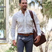 Man in white shirt, gray pants, carrying a Tom Beckbe brown bag with antique brass hardware.