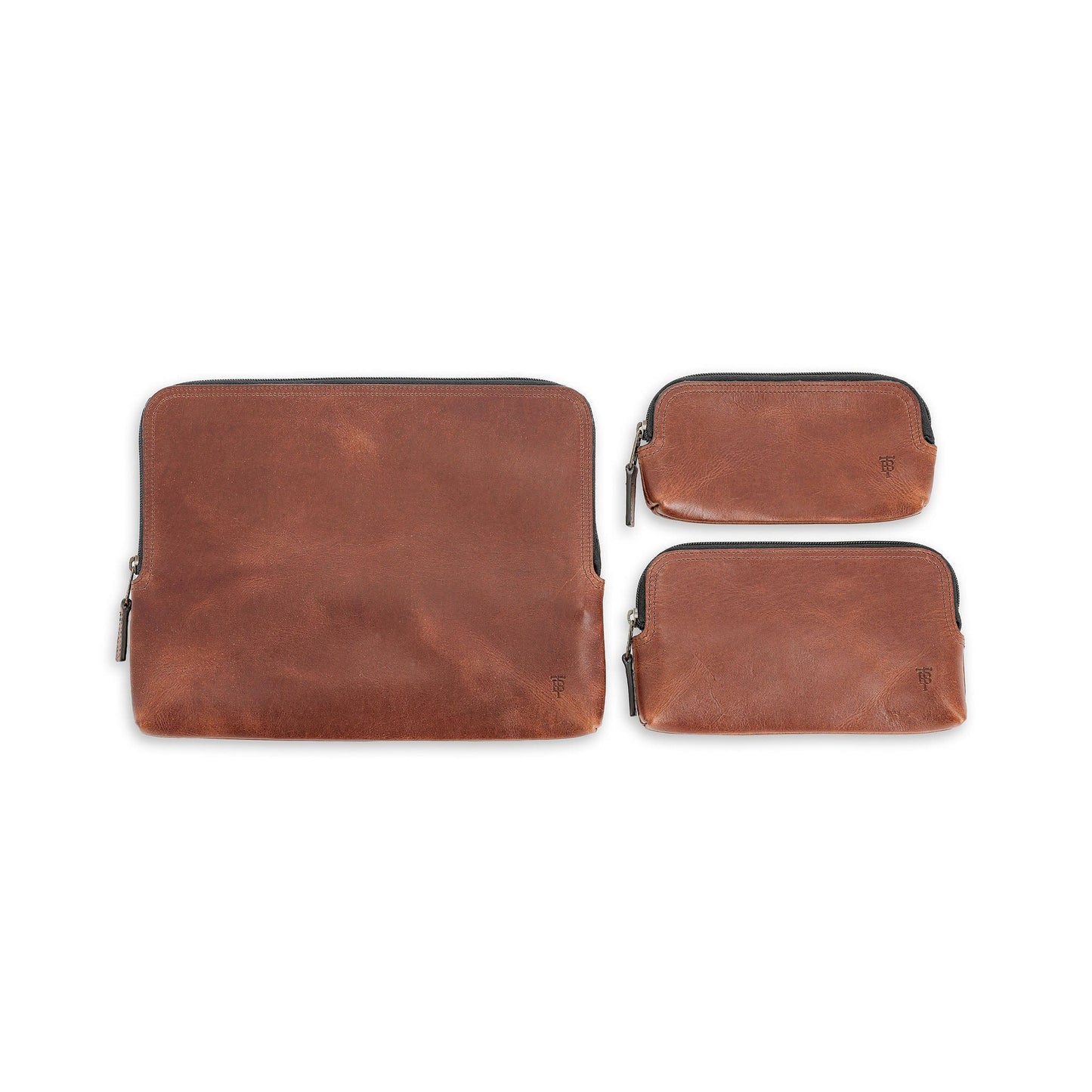 Three Tom Beckbe Leather Travel Pouches, full-grain with antique brass zippers, largest on left against white background.