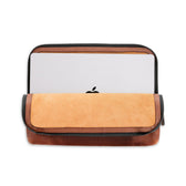 Laptop secure in Tom Beckbes Leather Travel Pouch with antique brass zipper, showing the Apple logo.
