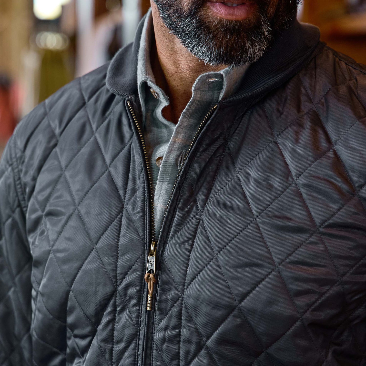 Close-up of a man wearing the Tom Beckbe Logan Bomber Jacket over a collared shirt, beard partially visible.