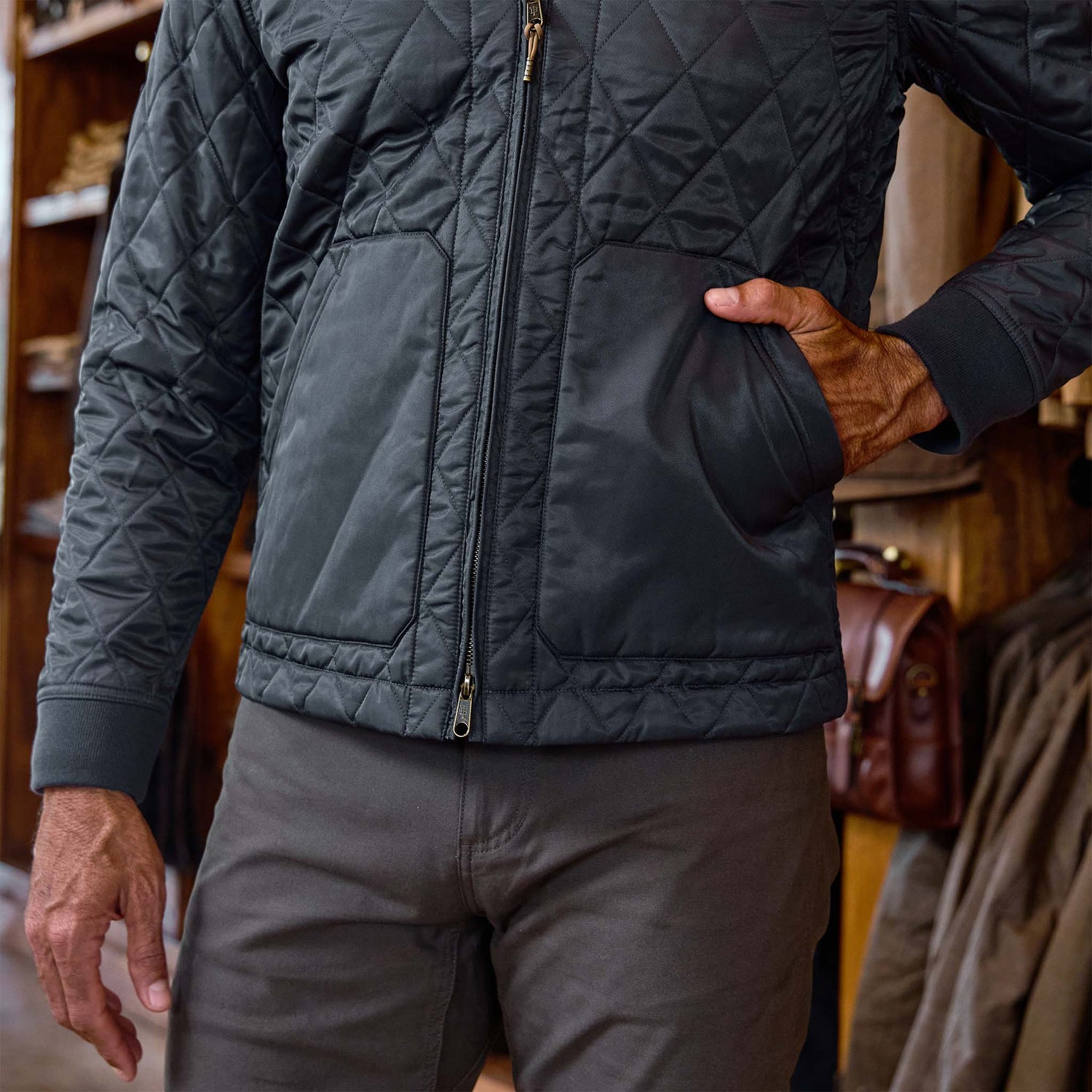 Person wearing a Tom Beckbe Logan Bomber Jacket and gray pants, standing indoors with one hand in the jacket pocket.