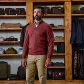 Man wearing a Tom Beckbe York Merino Quarter Zip in rust with khaki pants, standing in a clothing store.