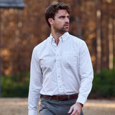 Man wearing the Tom Beckbe Monroe Poplin Shirt and gray pants outdoors with trees in the background.