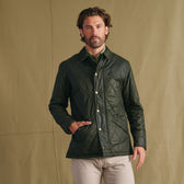 Man wearing Tom Beckbe Paddock Quilted Jacket and beige pants stands before a plain tan background.