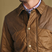 Man wearing Tom Beckbe Paddock Quilted Jacket over a checkered shirt; only upper torso and jacket visible.