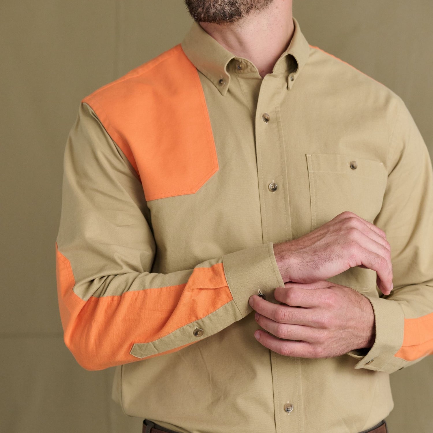 Man wearing a Tom Beckbe Perry Field Shirt adjusts his cuff, ready for a day in the upland field.