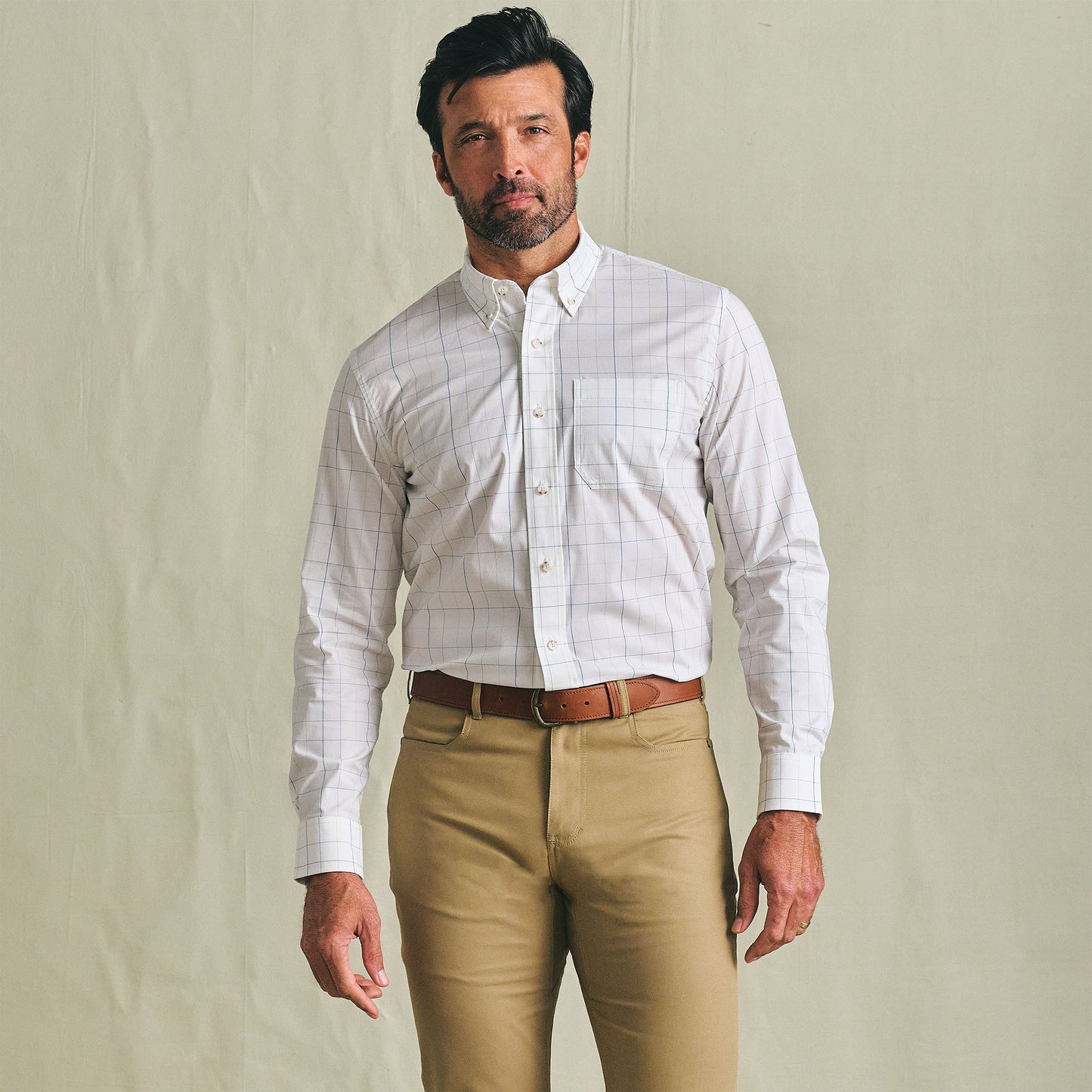 Man wearing a Tom Beckbe Powell Performance Shirt and khaki pants, standing against a plain light-colored background.