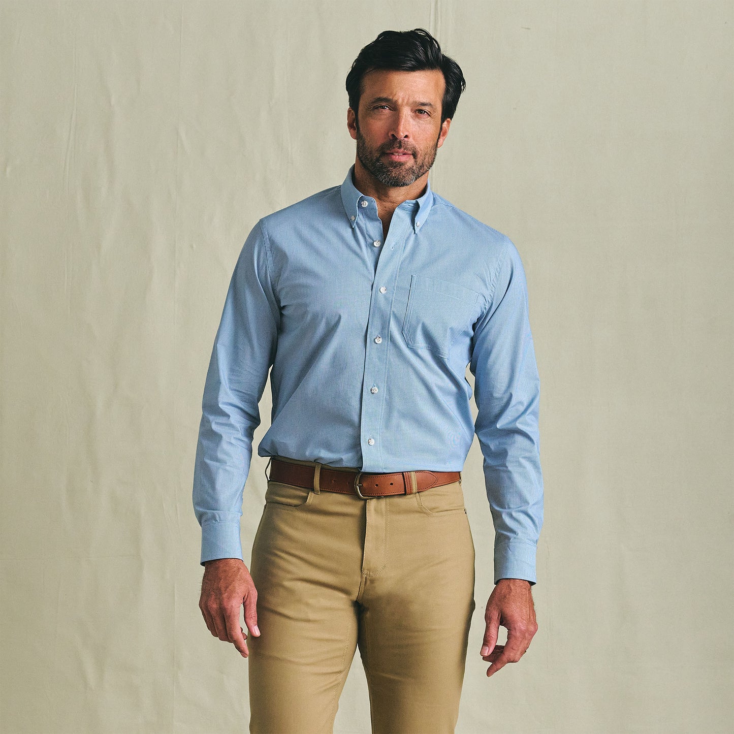 Man wearing Tom Beckbe's Powell Performance Shirt (UPF 30+) and khaki pants against a beige background.