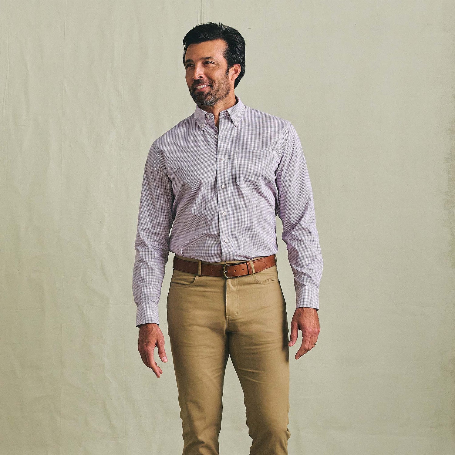 Man in Tom Beckbe Powell Performance Shirt and khaki pants stands against a plain, light background.