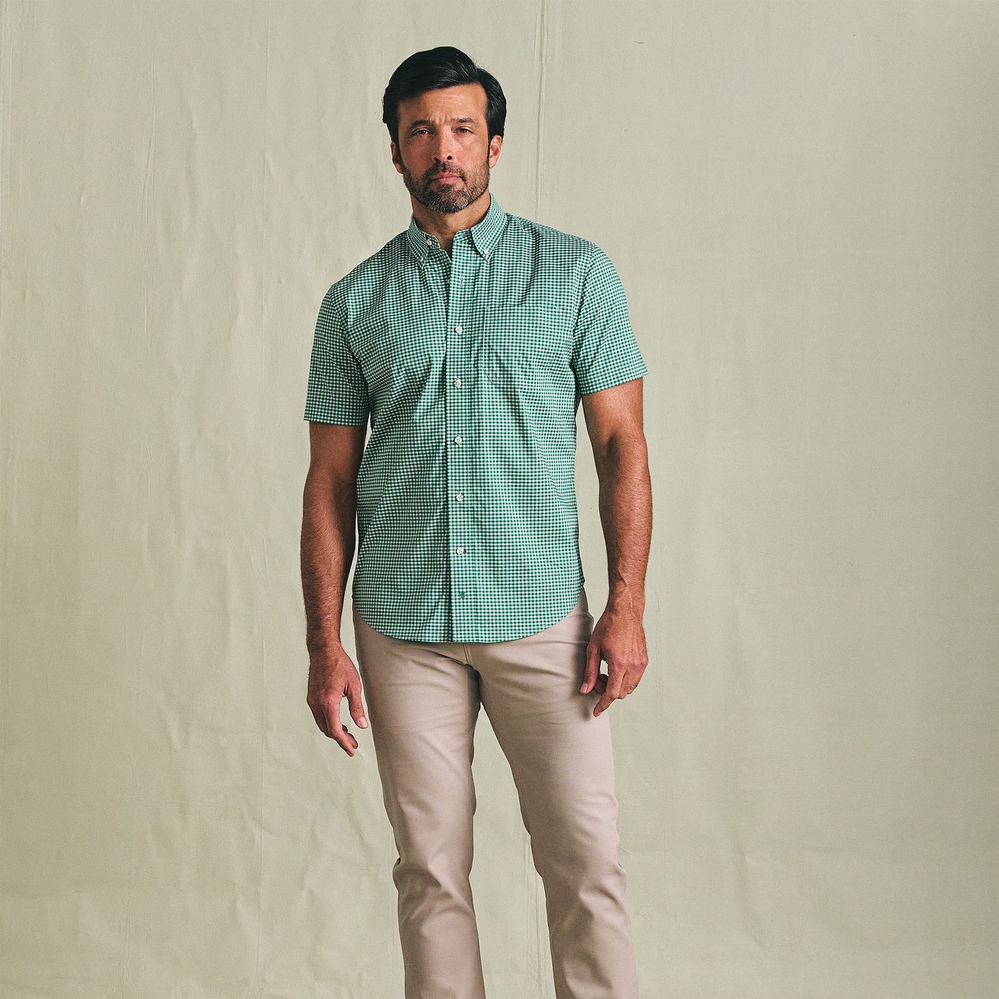Man wearing Tom Beckbe’s Powell Performance Shirt (Short Sleeve) and light beige pants against a plain background.