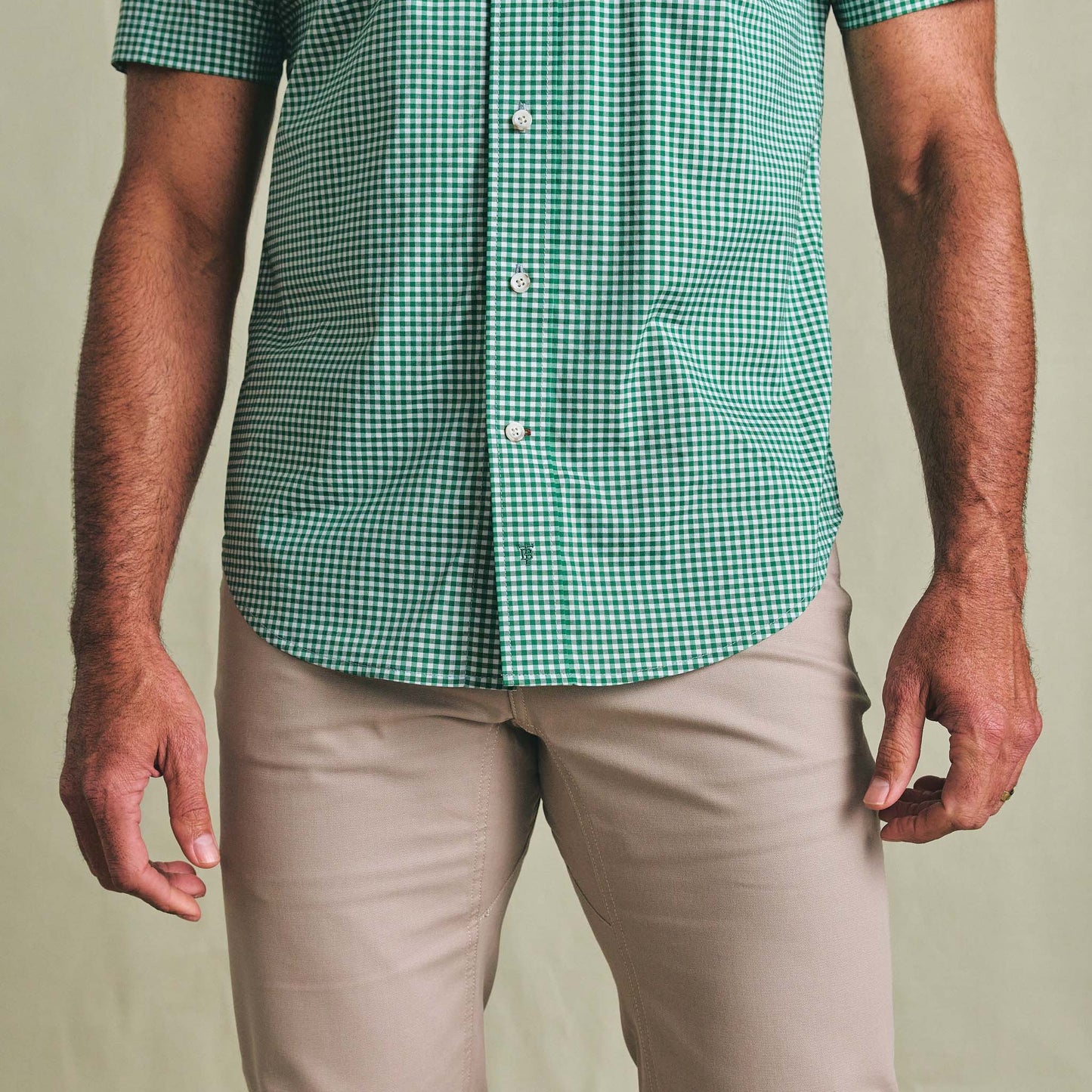 A person in a green Powell Performance Shirt (Short Sleeve) by Tom Beckbe and beige pants, shown shoulders to mid-thigh.