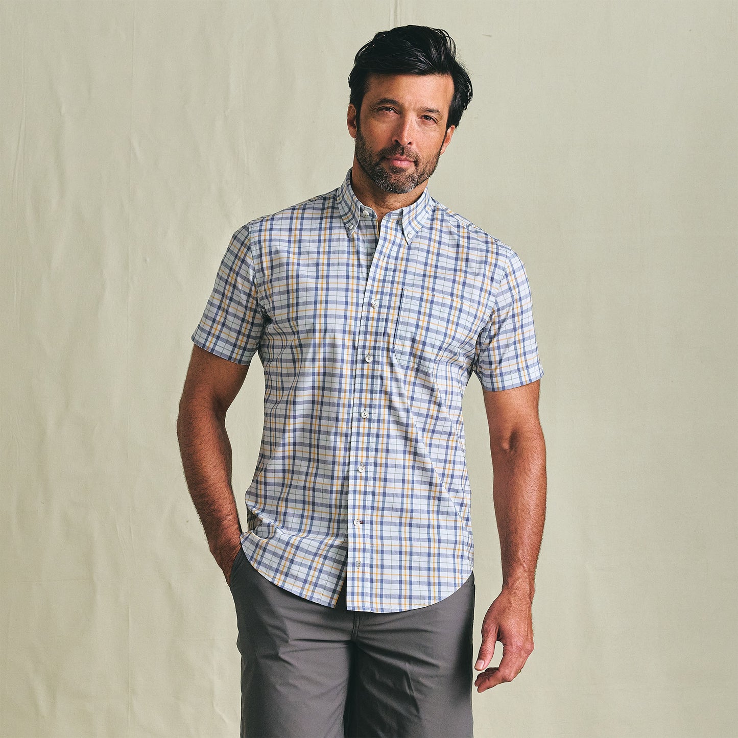 Man in a Tom Beckbe Powell Performance Shirt (Short Sleeve) and gray shorts stands against a plain background.