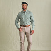 A man wears the Tom Beckbe Powell Performance Shirt, a green UPF 30+ shirt, with beige pants and a brown belt.