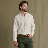 Man wearing a Tom Beckbe Prescott Estate Twill Shirt and olive green pants stands before a plain brown background.